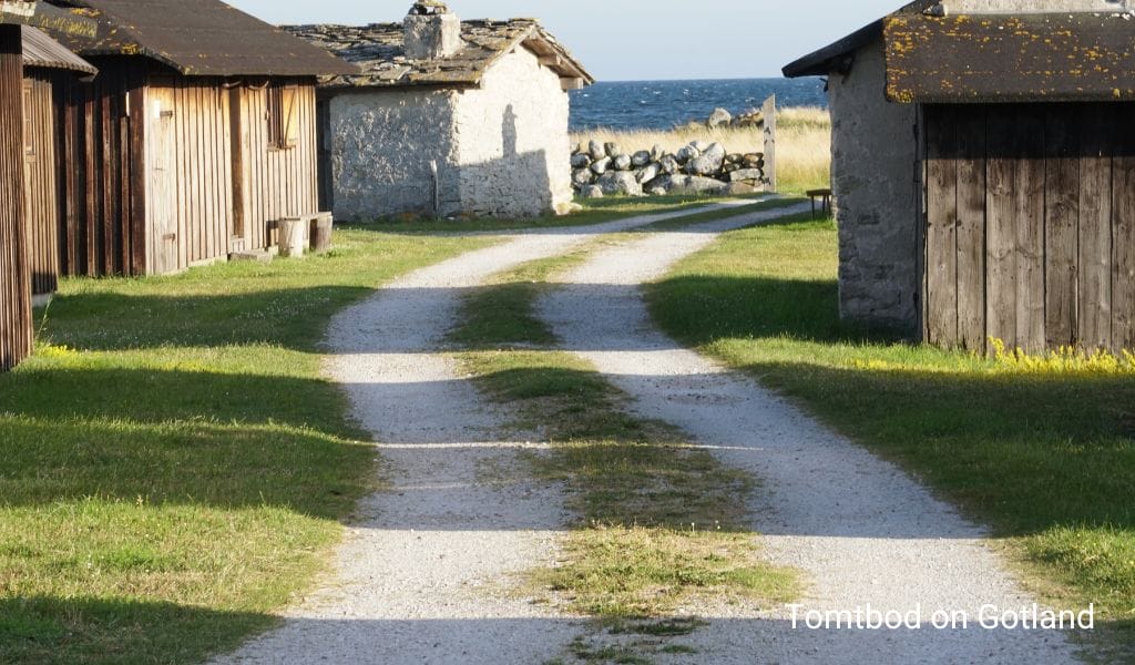 A charming path winding through an old village on Gotland, Sweden, lined with historic stone buildings and lush greenery.