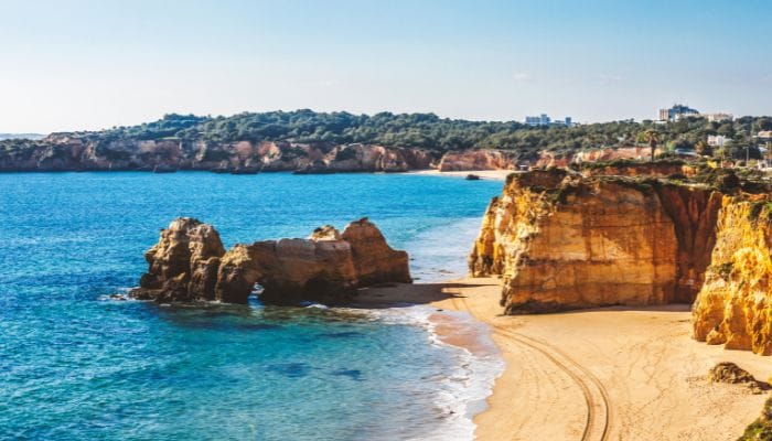 The stunning beaches of Algarve, Portugal, offer golden sand and clear turquoise waters, perfect for a relaxing getaway.