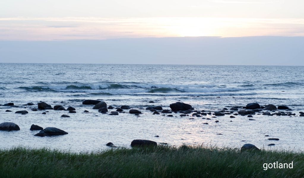 The Baltic Sea off the coast of Gotland, Sweden, with rough stones illuminated by the warm glow of the setting sun