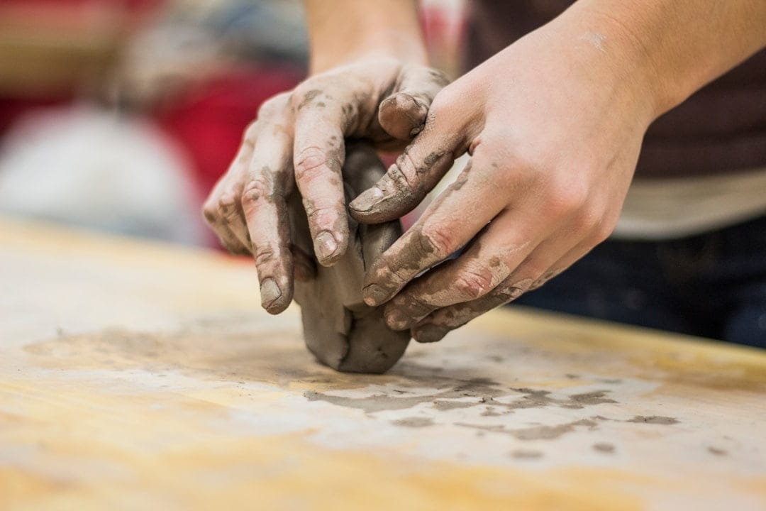 Hands working with wet clay, illustrating work-life balance