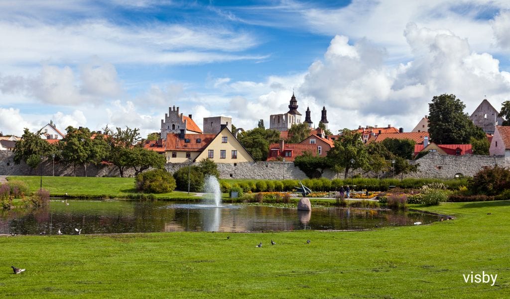 Scenic view of Visby with a lush meadow and serene pond in the foreground, and the historic town in the background on Gotland Island, Sweden